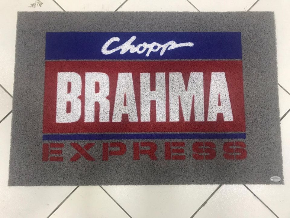 Capacho emborrachado cinza personalizado com a logomarca Chopp Brahma Express em azul e vermelho, base resistente e antiderrapante sobre piso de cerâmica, fotografia realista de tapete comercial para bar e conveniência